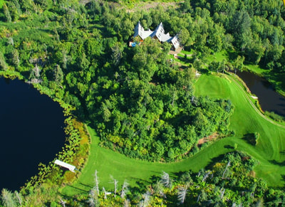 An aerial view of the Ridgewood Lodge, 2 ponds, and vast lawns and gardens. 