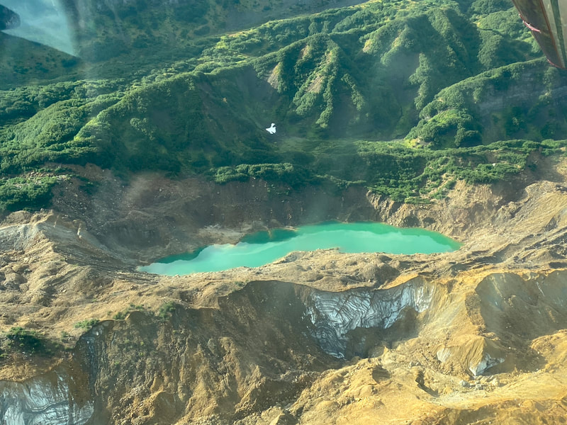 An aerial view of a uniquely-green-colored mountain lake. 