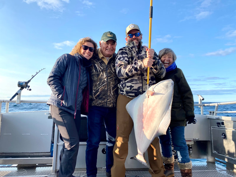 A family holding a large Halibut on their fishing charter. 