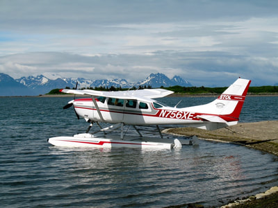 A beautiful red and white float plane pulled up at a beach on the Alaska Peninsula. 